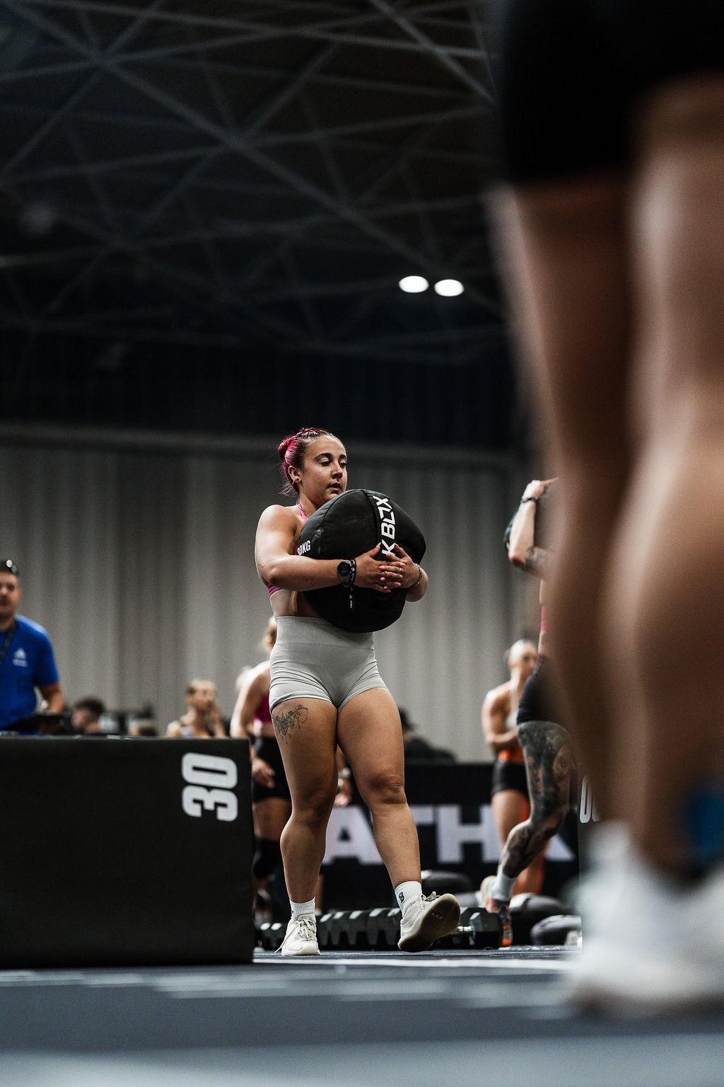 An athlete carries a sandbag across the competition floor